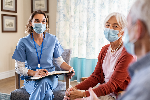Healthcare professional sitting with two patients in their home